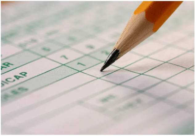 Close-up of a pencil marking a golf scorecard, focusing on scoring strategy.